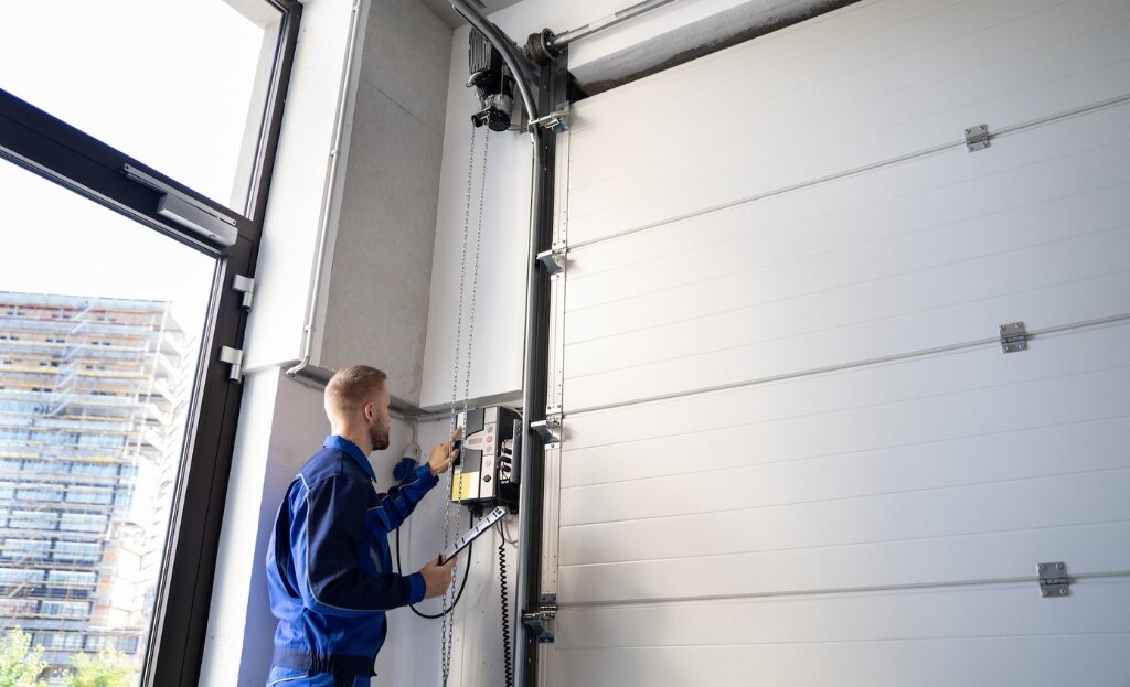 Technician servicing the opener mechanism on a large commercial sectional garage door