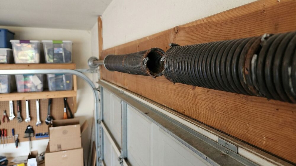 Close-up of a broken garage door torsion spring on the shaft above the door