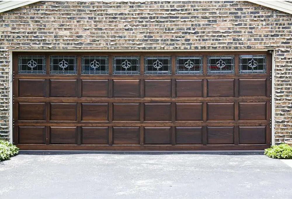 Custom stained wood carriage-house garage door with decorative windows on a brick home