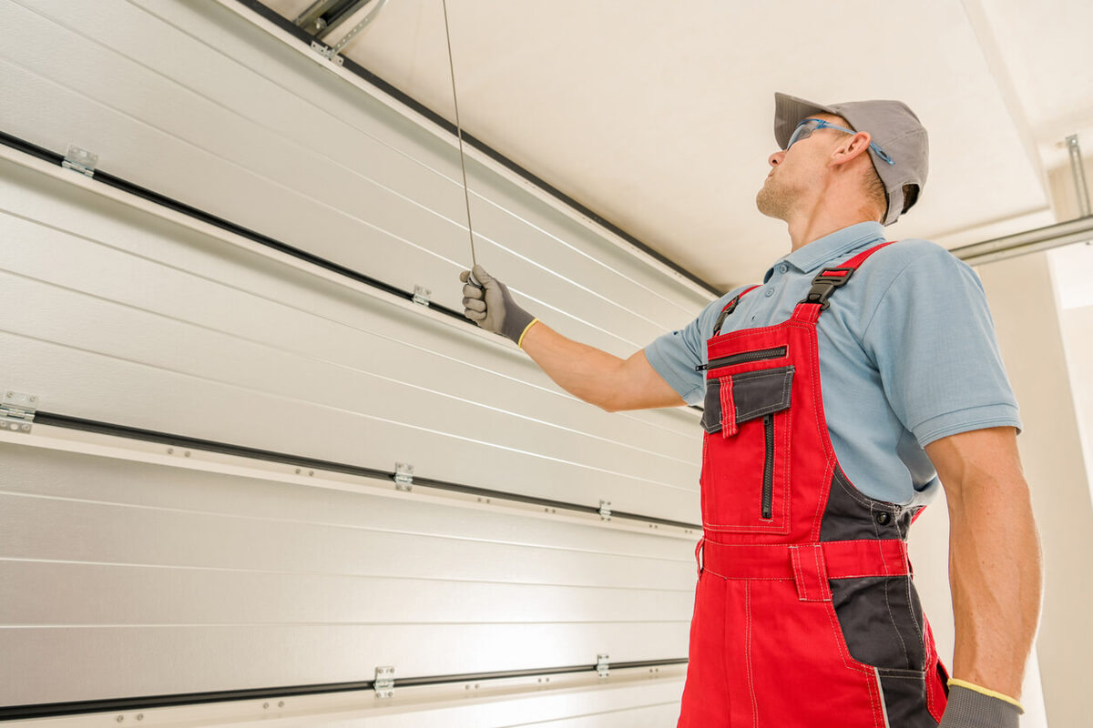 A technician servicing the top section of a residential garage door