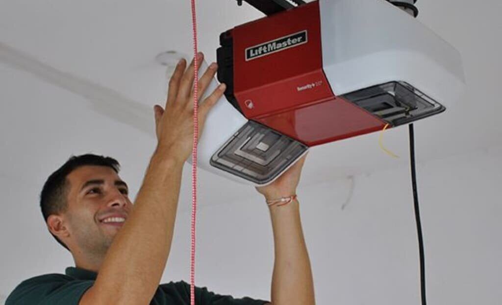 A G Brothers technician installing a LiftMaster garage door opener on the ceiling