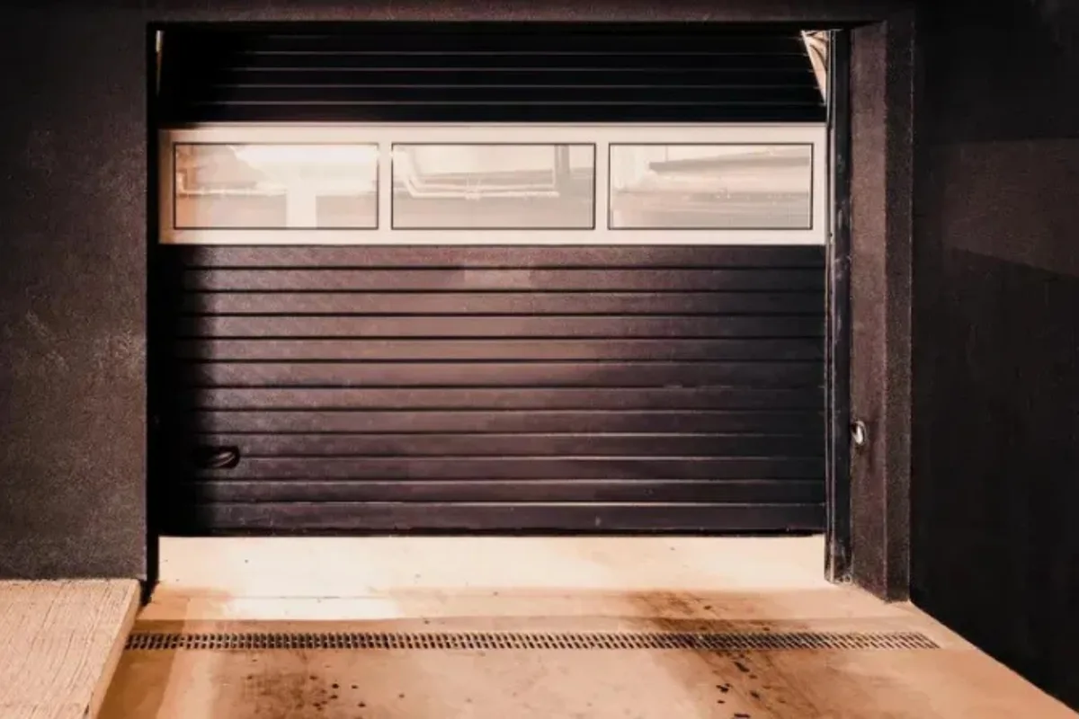 A black sectional overhead garage door partly raised on its tracks, the most common overhead door type